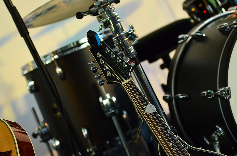 black electric guitar beside a black drumset